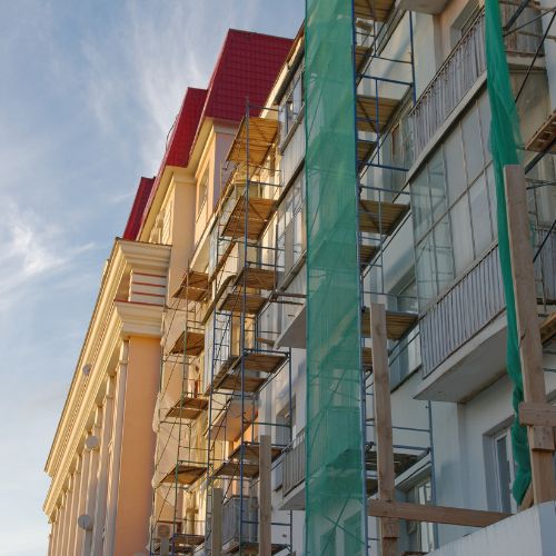 Edificio en renovación con andamios y malla verde en la fachada