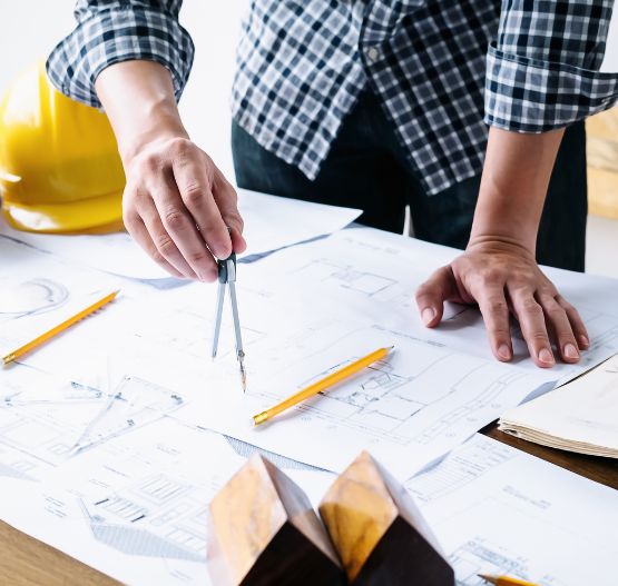 Arquitecto o ingeniero trabajando con planos de construcción y compás sobre una mesa
